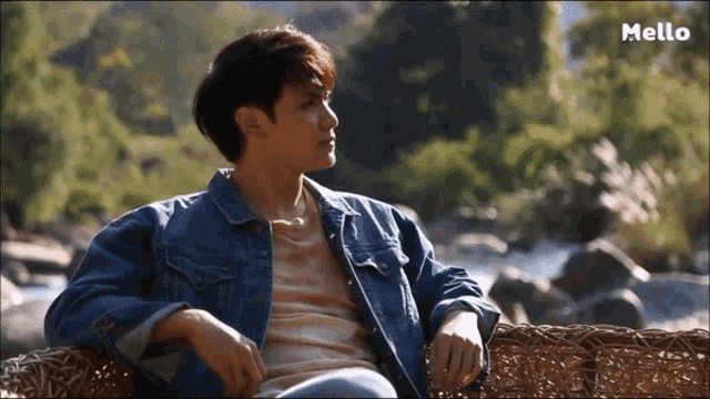 a man in a denim jacket sits on a wicker chair with mello written on the bottom right