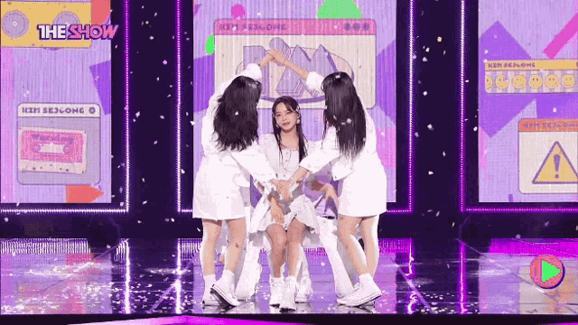a group of girls are dancing on a stage in front of a screen .
