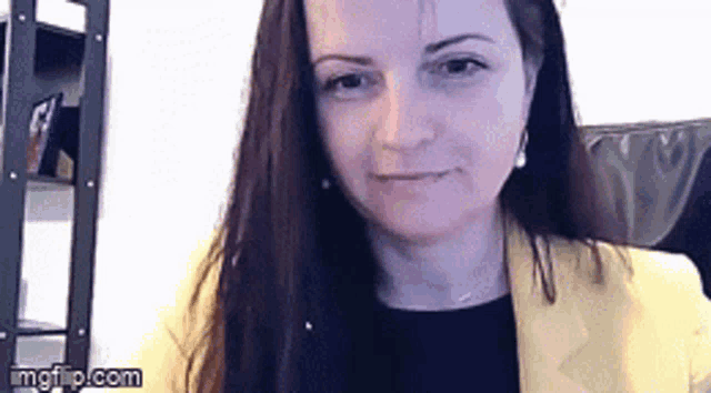 a woman wearing a yellow jacket and a black shirt is sitting in a chair .