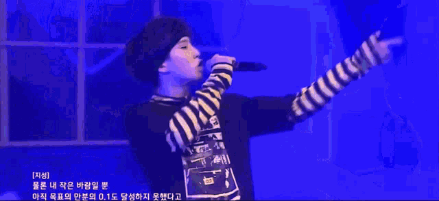 a man singing into a microphone with chinese writing on the bottom right