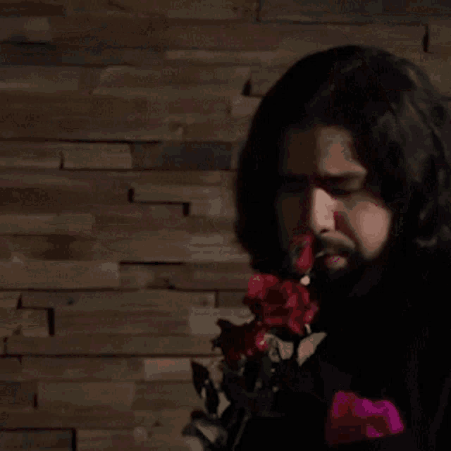 a man in a black suit is holding red roses