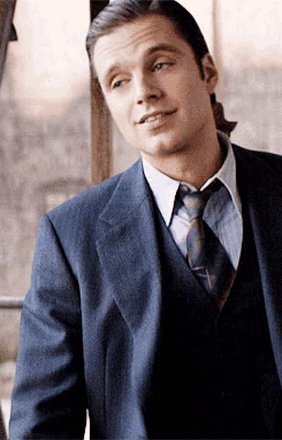 a man in a suit and tie looks to the side