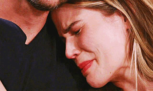 a woman is crying while hugging a man .