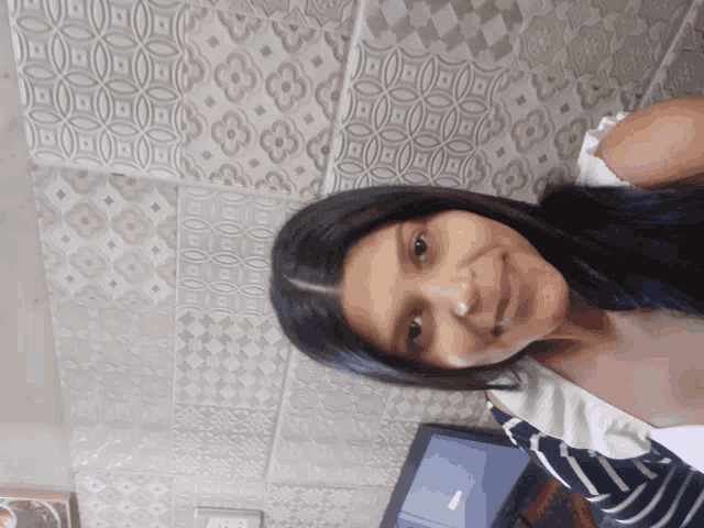 a woman is smiling in front of a wall that has a pattern