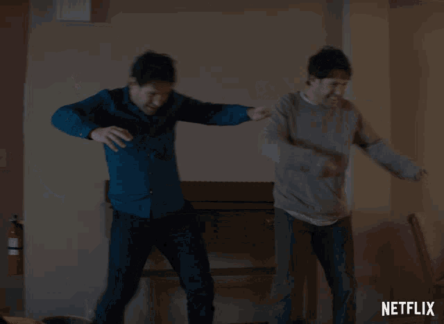 two men are dancing in front of a wall that says netflix on it