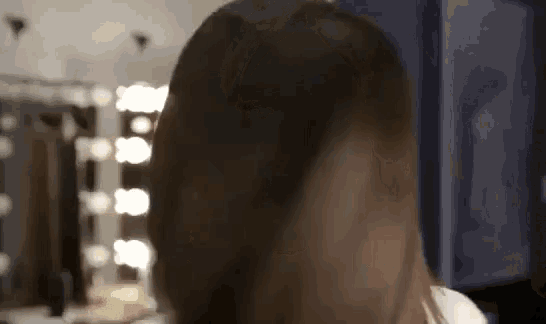 a woman is blow drying her hair in front of a mirror in a beauty salon .