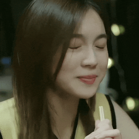 a woman with her eyes closed is holding chopsticks
