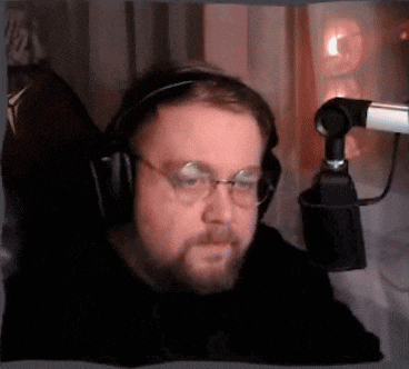 a man wearing headphones and glasses sitting in front of a microphone
