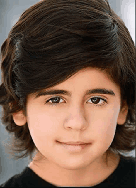 a close up of a young boy 's face with a black shirt