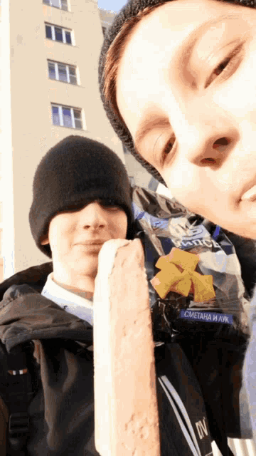 two boys are posing for a picture and one of them is holding a bag that says " сметана и лук " on it
