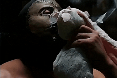 a man wearing a mask holds a stuffed animal