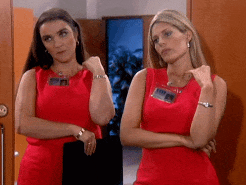 two women standing next to each other wearing red dresses