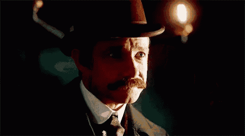 a man in a suit and tie is smoking a cigarette in a dark room .