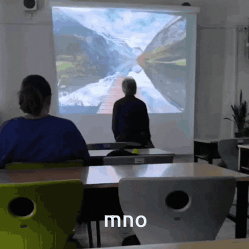 two people sitting in front of a projector screen with the word mno on the bottom right