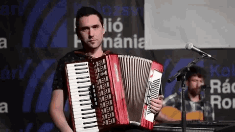 a man is playing an accordion in front of a sign that says ' hungaria ' on it
