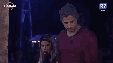 a man and a woman are standing next to each other in front of a sign that says r7