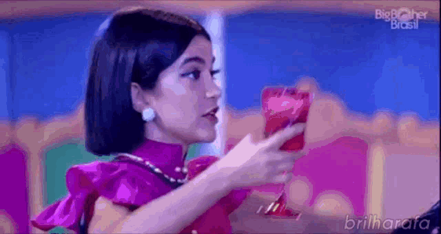 a woman in a pink dress is holding a glass of wine in her hand .