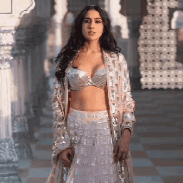 a woman in a crop top and a skirt is standing in a room .