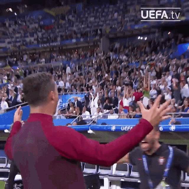 a man stands in front of a crowd in a stadium with uefa.tv written on the bottom