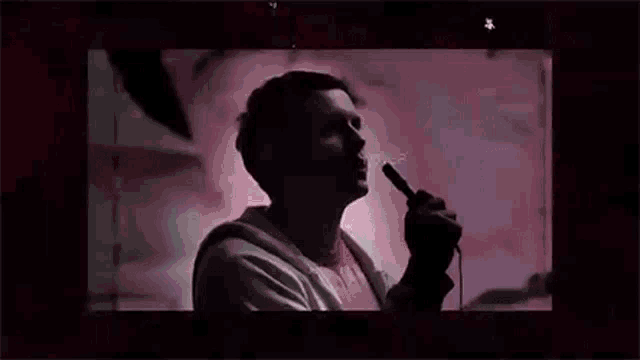 a man is singing into a microphone with the word not written on the screen .