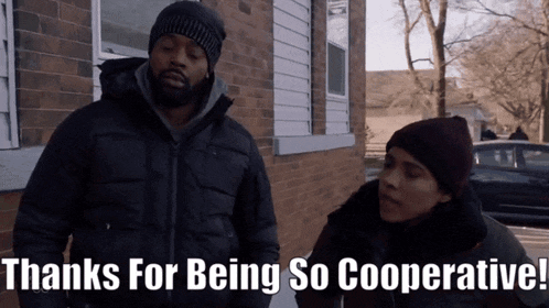 a man and a woman are standing in front of a brick building and the words thanks for being so cooperative