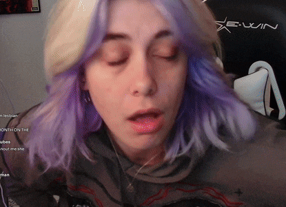 a woman with purple hair is wearing headphones and a hoodie