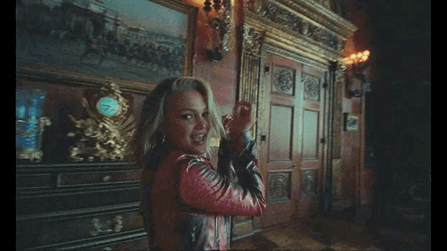 a woman in a red jacket stands in a dark room