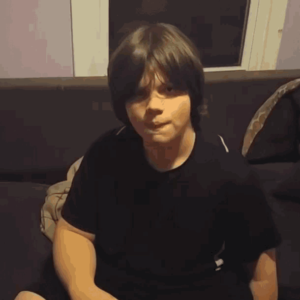 a young boy sitting on a couch with the word yes written on his shirt