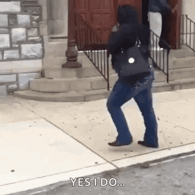a woman is walking down a sidewalk while holding a purse and talking on a cell phone .