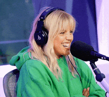 a blonde woman wearing headphones and a green hoodie with the word lg on it