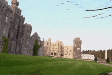 a large castle with a lush green lawn in front of it .