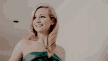 a woman in a green dress is smiling and looking up .