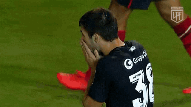 a soccer player wearing a black jersey with the number 5 on it is kneeling down on the field .
