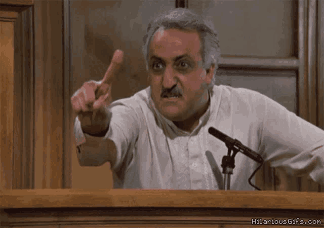 a man giving a speech in front of a microphone with hilariousgifs.com on the bottom right