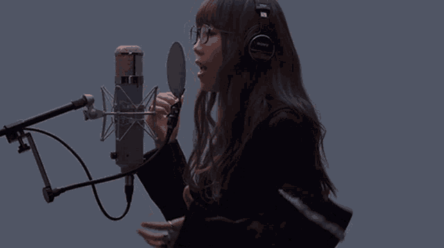 a woman singing into a sony microphone with headphones on