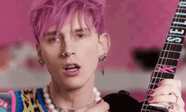 a young man with pink hair is playing a guitar .
