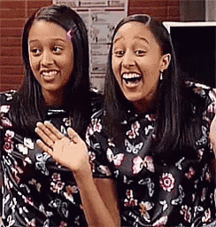 two girls are sitting next to each other and smiling .