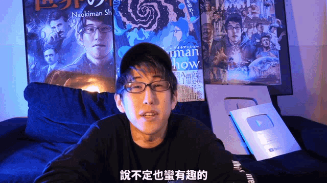 a man sitting in front of a poster that says naokiman shi