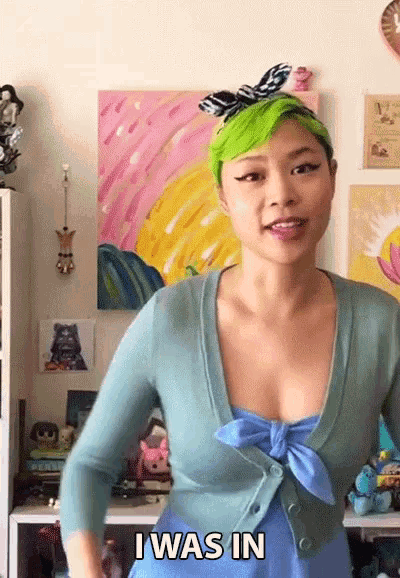 a woman with green hair says " i was in " in front of a painting
