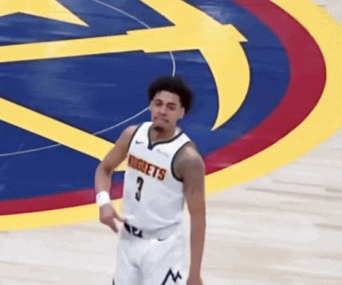 a man wearing a nuggets jersey stands on a basketball court