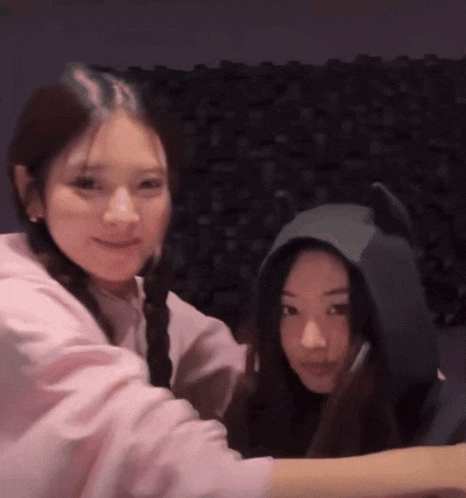 two girls are posing for a picture and one is wearing a hoodie with cat ears