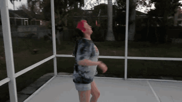 a woman in a tie dye shirt is dancing in a screened in area