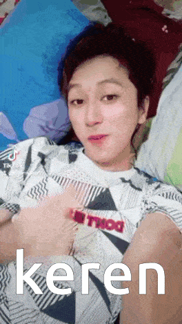 a man is laying on a bed with the word keren written on the bottom of his face .