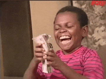 a young boy is laughing while holding a bunch of money .