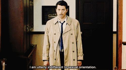 a man in a trench coat and tie stands in a hallway and says i am utterly indifferent to sexual orientation