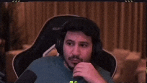 a man wearing headphones is sitting in front of a microphone .
