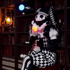 a black and white clown is sitting in front of a bookcase