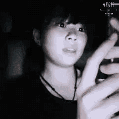 a woman is holding a cell phone in her hand and looking at it in the dark .