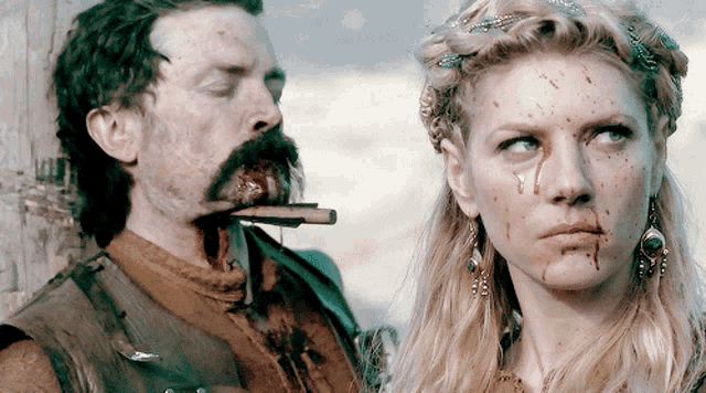 a woman with blood on her face stands next to a man with blood on his face