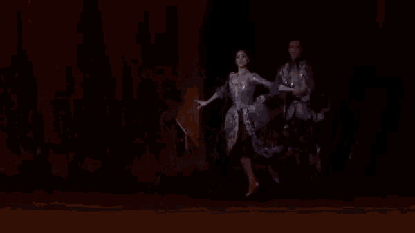 a man and a woman are dancing on a stage in a dark room .
